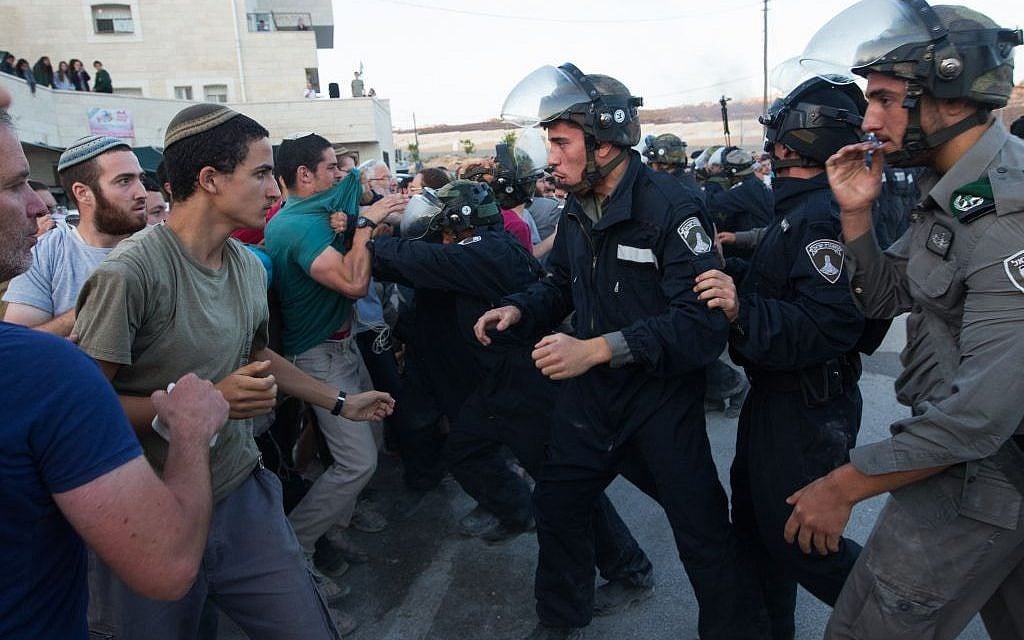 Israeli security forces scuffle with settlers who had barricaded themselves in an attempt to prevent the demolition of illegally constructed buildings, at the Jewish settlement of Beit El, near the West Bank town of Ramallah, on July 28, 2015. (Nati Shohat/FLASH90)