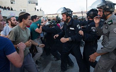 Israeli security forces scuffle with settlers who had barricaded themselves in an attempt to prevent the demolition of illegally constructed buildings, at the Jewish settlement of Beit El, near the West Bank town of Ramallah, on July 28, 2015. (Nati Shohat/FLASH90)