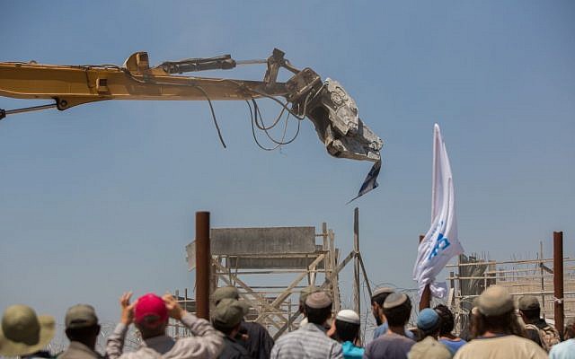 A tractor grabs an Israel flag as it tears down homes in the Beit El settlement July 29, 2015. (Yonatan Sindel/Flash90) A tractor grabs an Israel flag as it tears down homes in the Beit El settlement July 29, 2015. (Yonatan Sindel/Flash90)