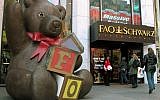 In this Nov. 10, 2003 file photo, customers pass a statue of a teddy bear and a doorman dressed as a toy soldier as they enter the FAO Schwarz on Fifth Avenue in New York. The store is closing its doors for good on Wednesday, July 15, 2015, though it may reopen elsewhere in midtown Manhattan. (AP Photo/Rich Kareckas, File)
