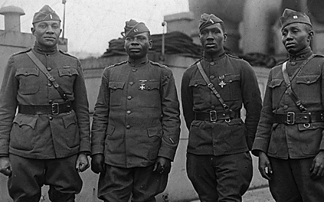 Officers of the United States Army's segregated 366th Infantry Regiment on board the Aquitania, en route home from World War I service. Left to right: Lieutenant C.L. Abbot, South Dakota; Captain Joseph L. Lowe, Pacific Grove, California; Lieutenant Aaron R. Fisher, Lyles, Indiana, recipient of Distinguished Service Cross; Captain E. White, Pine Bluff, Arkansas (Wikimedia Commons/Public domain)
