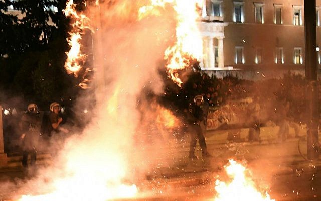 Riot policemen try to avoid a petrol bomb thrown by anti-austerity protesters during a rally outside the Greek Parliament in Athens, Wednesday, July 22, 2015. (AP Photo/Giannis Papanikos)