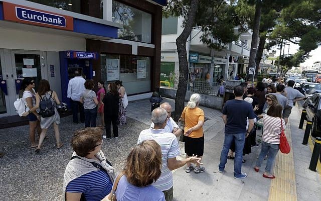 People stand in queues as they wait to use the ATMs of two banks in Athens on Saturday, July 4, 2015. (AP/Thanassis Stavrakis)
