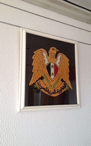 An embroidery of the national Syrian emblem hangs on the wall of Sheikh Hayel Sharaf, July 8, 2015 (Elhanan Miller/Times of Israel) 