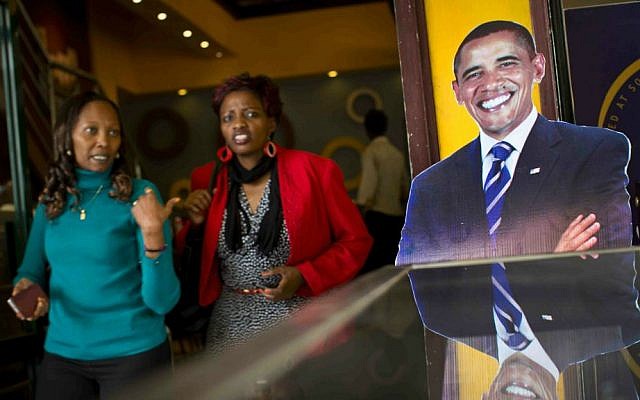 Customers walk past a cardboard cutout of President Barack Obama in the entrance way of the Cafe Deli coffee shop in Nairobi, Kenya, Wednesday, July 22, 2015. (AP Photo/Ben Curtis)