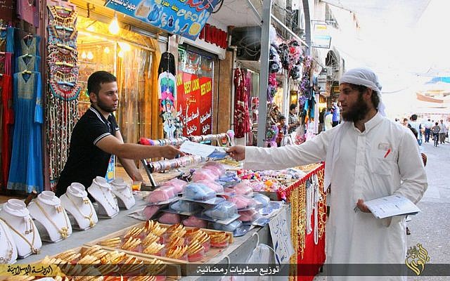In this Tuesday, June 16, 2015 photo provided by a website of the Islamic State group, an IS member, right, distributes pamphlets about fasting before the Muslim holy month of Ramadan in Mosul, northern Iraq.  (Islamic State militant via AP)