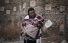 In this Friday, Oct. 8, 2010, file photo, an Israeli woman of the Women of the Wall organization wears tefillin, a leather strapped box containing Torah scripture which is used for prayer, as she holds a Torah and prepares to pray at the Western Wall, the holiest site where Jews can pray in Jerusalem's old city. (AP Photo/Tara Todras-Whitehill, File)