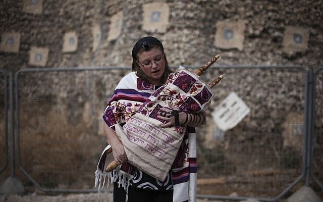 In this Friday, Oct. 8, 2010, file photo, an Israeli woman of the Women of the Wall organization wears tefillin, a leather strapped box containing Torah scripture which is used for prayer, as she holds a Torah and prepares to pray at the Western Wall, the holiest site where Jews can pray in Jerusalem's old city. (AP Photo/Tara Todras-Whitehill, File)