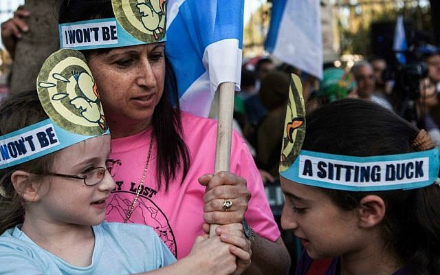 Israelis hold flags during a demonstration outside the prime minister's residence in Jerusalem on Wednesday, July 1, 2015, calling on Prime Minister Benjamin Netanyahu to act against recent Palestinian attacks against Israelis. (AP Photo/Dan Balilty)