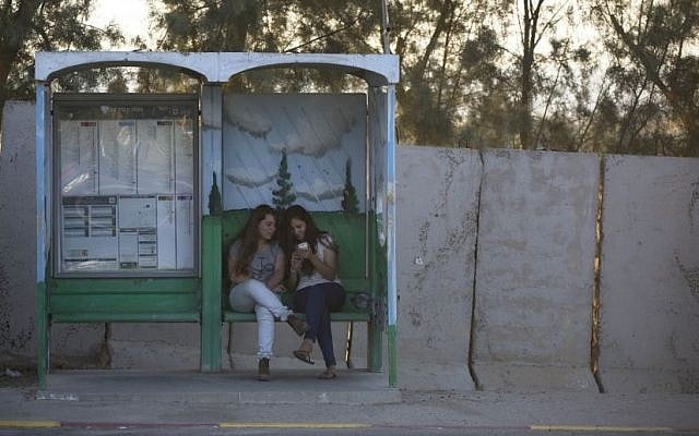 Israeli girls wait for transportation in a bus stop protected with concrete blocks near the southern Israeli town of Sderot, next to the Israel-Gaza border, June 30, 2015. (AP Photo/Oded Balilty)