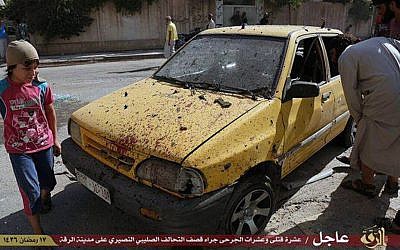 This Saturday, July, 4, 2015 photo provided by a website of the Islamic State group, shows people inspecting a car purportedly damaged by US-led airstrikes on Raqqa, Syria. (Islamic State militant website via AP)