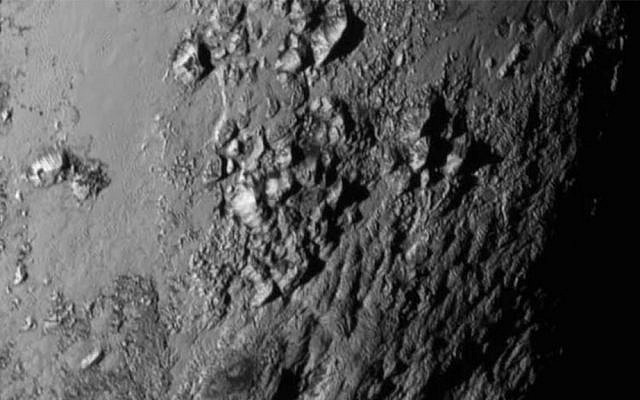 This Tuesday, July 14, 2015 image provided by NASA on Wednesday shows a region near Pluto's equator with a range of mountains captured by the New Horizons spacecraft. (NASA/JHUAPL/SwRI via AP)