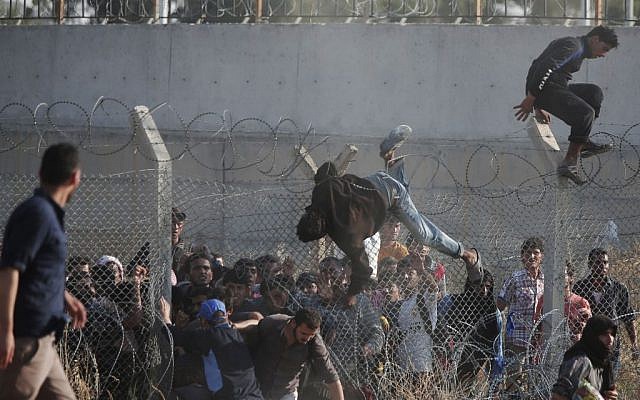 In this June 14, 2015, file photo, Syrian refugees cross into Turkey from Syria over and through a hole on the border fence in Akcakale, Sanliurfa province, southeastern Turkey. (AP Photo/Lefteris Pitarakis, File)