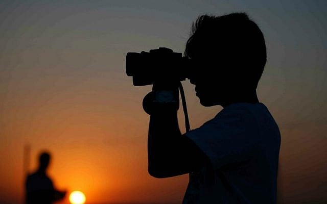 A youth uses binoculars to look at Turkish army tanks holding positions near the border with Syria, in the outskirts of the village of Elbeyi, east of the town of Kilis, in southeastern Turkey, Thursday, July 23, 2015. (AP Photo/Emrah Gurel)
