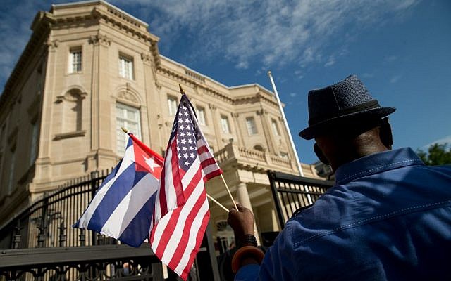 Edwardo Clark, a Cuban-American, holds an American flag and a Cuban flag as he celebrates outside the new Cuban embassy in Washington, Monday, July 20, 2015. (AP Photo/Andrew Harnik)