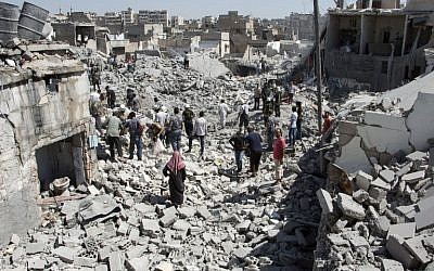 Syrians stand on the rubble of buildings after a missile fired by Syrian government forces hit a residential area in the Maghayir district in the old quarter of the northern Syrian city of Aleppo on July 21, 2015. (Photo by AFP Photo / Karam Al-Masri)