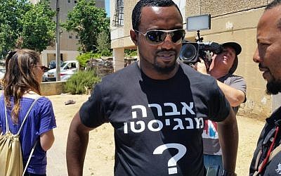 An activist with a T-shirt for Avraham Mengistu, who is currently believed to be held by Hamas in Gaza, outside his family’s home in Ashkelon, July 9, 2015. (Twitter)