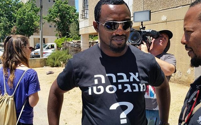 An activist with a T-shirt for Avraham Mengistu, who is currently believed to be held by Hamas in Gaza, outside his family’s home in Ashkelon, July 9, 2015. (Twitter)