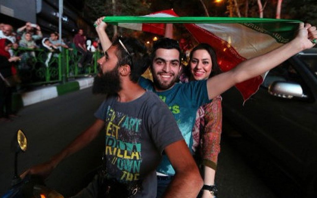 Iranians wave the national flag during celebrations in northern Tehran on July 14, 2015, after Iran's nuclear negotiating team struck a deal with world powers in Vienna (AFP/ATTA KENARE)