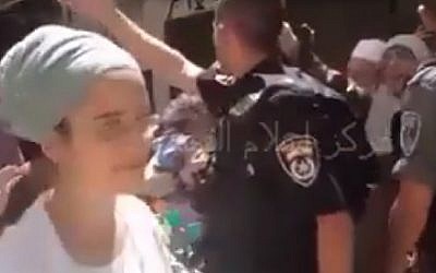 A Jewish woman, who was part of a group of Jewish visitors to the Temple Mount, is escorted by police officers from the site. In the clip, she calls the Prophet Muhammad a pig in response to heckling by a group of Muslim self-proclaimed guardians of the site. July 23, 2015 (Screenshot)