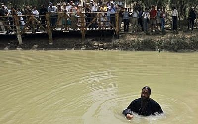 In this Tuesday, April 22, 2008 file photo, a Greek Orthodox Christian priest bathes in the Jordan River after it was blessed during a baptism ceremony at Qasr al-Yahud near Jericho in the West Bank, as people from Jordan's baptismal area, background, also watch the ceremony across the river. (AP Photo/Tara Todras-Whitehill, File)