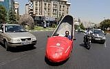 Iranian shoeshine man, Mohammad Ali Hassan Khani, whose nickname is Aliwaxima, drives his racy-red motorized stiletto on a street on August 19, 2015 in the capital Tehran. (AFP PHOTO / ATTA KENARE)