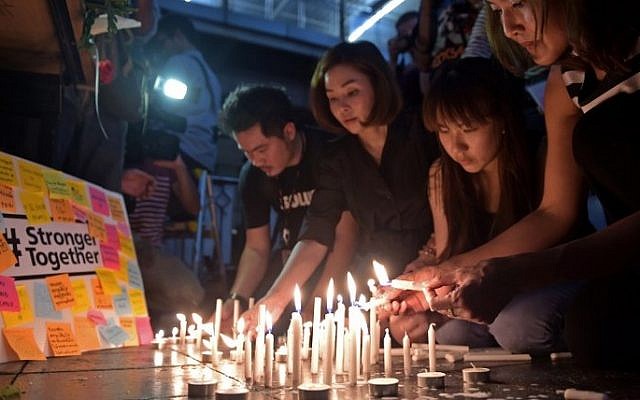 Thai office workers light candles for victims killed in a bomb blast outside a religious shrine in Bangkok on August 18, 2015. (AFP / PORNCHAI KITTIWONGSAKUL) Thai office workers light candles for victims killed in a bomb blast outside a religious shrine in Bangkok on August 18, 2015. (AFP / PORNCHAI KITTIWONGSAKUL)
