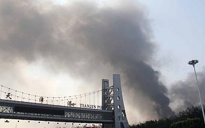 The Tianjin port gate is seen in the foreground as smoke rises from the site of a series of explosions in Tianjin on August 13, 2015.    (AFP)
