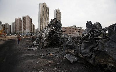 A man takes a photo of damaged cars at the site of the explosions in Tianjin on August 14, 2015.  Enormous explosions in a major Chinese port city killed at least 85 people and injured hundreds more, according to state media (AFP PHOTO)
