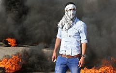 A Palestinian protester stands amid burning tires during clashes with Israeli security forces on a street leading to Duma village, on August 1, 2015 (Jaafar Ashtiyeh/AFP)