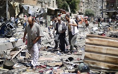 Syrians walk amid the rubble following air strikes by Syrian government forces on a marketplace in the rebel-held area of Douma, east of the capital Damascus, on August 16, 2015. (Sammer al Doumy/AFP)