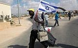 An African illegal migrant walks with an Israeli flag, following his release from the Holot Detention Centre in Israel's Negev desert, on August 25, 2015. (AFP PHOTO/MENAHEM KAHANA)