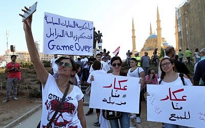 Lebanese young women take pictures as they hold placards before the start of an anti-government protest organised by a civil society frustrated with a political class they see as corrupt and incapable of providing basic services on August 29, 2015 at Beirut's iconic Martyrs Square. (AFP/ ANWAR AMRO)