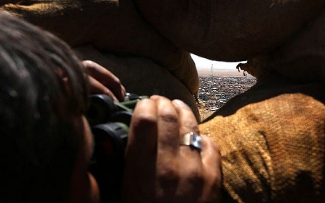 An Iraqi Kurdish Peshmerga fighter monitors the area with binoculars as he holds a position behind sandbags on the front line near the northern Iraqi town of Sinjar, west of Mosul, on August 17, 2015. (AFP Photo/Safin Hamed)