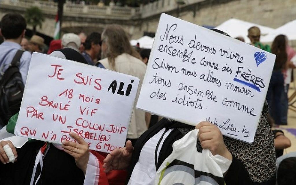 People hold placards reading "I am Ali, 18 months, burned alive by a Jewish Israeli colonist, who only took 6 months" (L), and "We should live together as brothers, or we will all die together as idiots" (R) as part of  "Gaza Plages" (Gaza Beach), near the "Tel-Aviv sur Seine" beach attraction during the 14th edition of Paris Plages (Paris Beaches) in central Paris, on August 13, 2015. (Kenzo Tribouiilard/AFP)