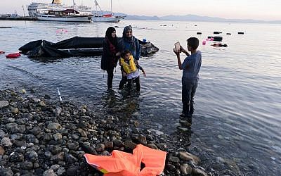 Syrian migrants take a picture after their safe arrival  on an overcrowded dinghy to the coast of the southeastern Greek island of Kos from Turkey, on August 15, 2015. (AFP/LOUISA GOULIAMAKI)