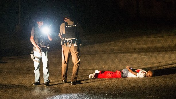 Police stand over Tyrone Harris after a shoot out along West Florissant Street during a demonstration to mark the one-year anniversary of the shooting of Michael Brown on August 9, 2015 in Ferguson, Missouri (Scott Olson/Getty Images/AFP)