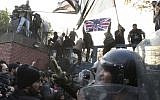 Iranian police officers trying prevent protesters from storming the British Embassy, as others stand on the gates holding a satirized British flag and Islamic flags, in Tehran, Iran, Tuesday, Nov. 29, 2011. (Photo/Vahid Salemi)