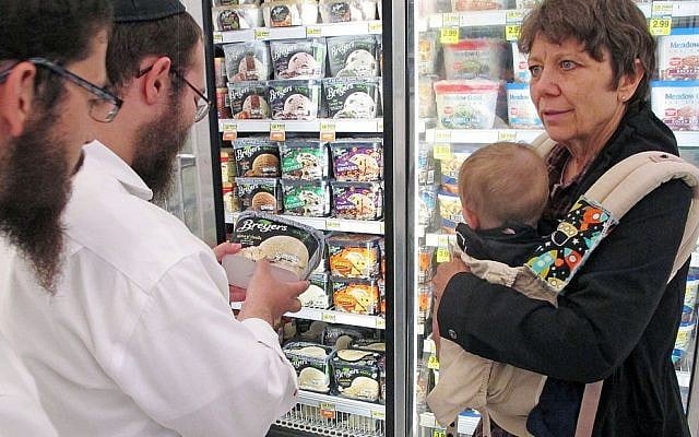 In this July 27, 2015 photo, Orthodox Jewish rabbi Dovid Lepkivker, center, examines a container of Breyer's ice cream, which happens to be kosher, as fellow rabbi Eli Chaikin, left, and Mary Semple look on in Helena, Mont.  (AP/Matt Volz)