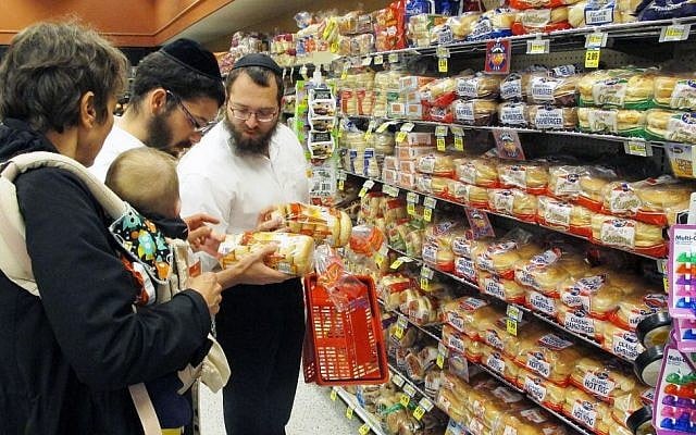 In this July 27, 2015 photo, orthodox Jewish rabbis Dovid Lepkivker, right, and Eli Chaikin, center, inspect packages of bagels with Mary Semple, left, and her grandson Levi Weitner in a grocery store in Helena, Mont.  (AP/Matt Volz)