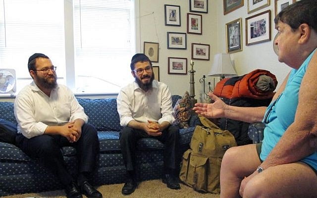 In this July 27, 2015 photo, Orthodox Jewish rabbis Dovid Lepkivker, left, and Eli Chaikin, center, listen as Beth Pagel talks about being Jewish in Montana, in Helena, Mont.  (AP/Matt Volz)