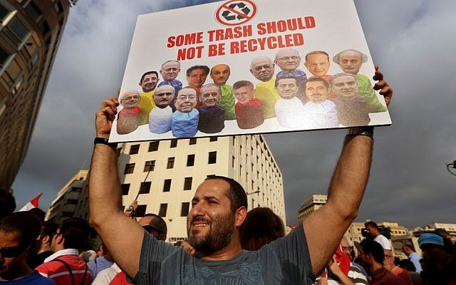 In this August 22, file photo, a Lebanese activist holds a poster with pictures of Lebanese Cabinet ministers during a protest against the ongoing trash crisis, in downtown Beirut, Lebanon. (AP Photo/Bilal Hussein, File) In this August 22, file photo, a Lebanese activist holds a poster with pictures of Lebanese Cabinet ministers during a protest against the ongoing trash crisis, in downtown Beirut, Lebanon. (AP Photo/Bilal Hussein, File)