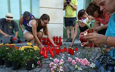 People light candles in front of the police station in Eisenstadt, Austria, Thursday, Aug 27, 2015. Austrian police on Thursday discovered the badly decomposing bodies of 71 migrants stacked in a truck parked on the shoulder of the main highway from Budapest to Vienna near Eisenstadt. (AP Photo/Ronald Zak)