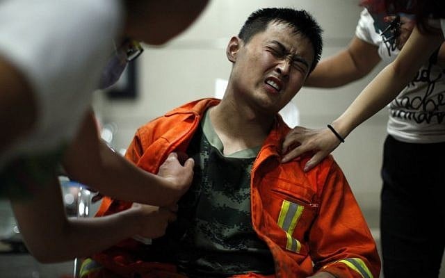 An injured firefighter grimaces as he is examined in a hospital following explosions in northeastern China's Tianjin municipality Aug. 13, 2015. (Chinatopix Via AP)