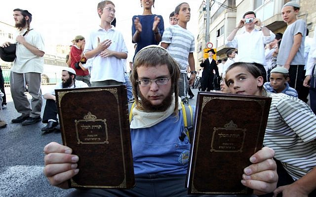 An Orthodox young man holds up copies of the book Torat Hamelech in which it is stated that the killing of non-Jews is permitted in certain situations, July 3, 2011 Nati Shohat/Flash90