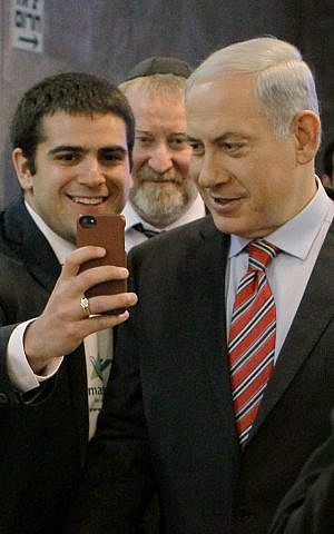Prime Minister Benjamin Netanyahu seen with a Masa student taking a selfie photo on his phone before the start of the weekly cabinet meeting at the Prime Minister's Office in Jerusalem on March 30, 2014. (Danny Meron/POOL/Flash90)