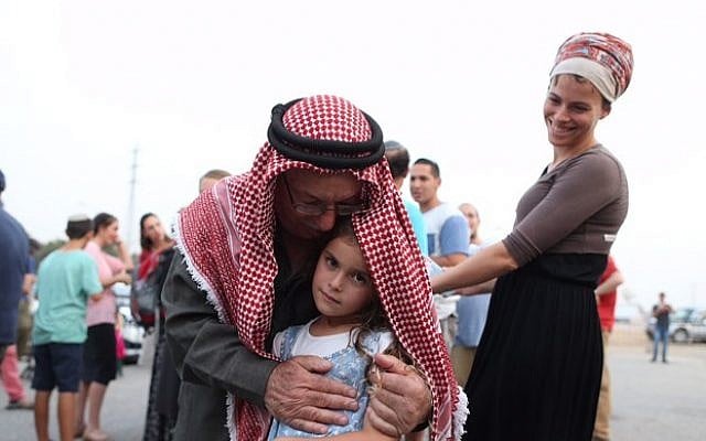 Sheikh Ibrahim Ahmad Abu El-Hawa embraces an Israeli girl at a prayer vigil at the Etzion Junction for the Dawabsha family on Sunday. (Nati Shohat/Flash90)