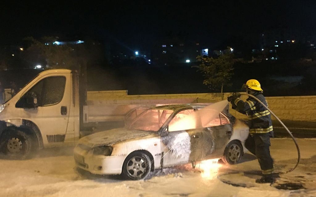 Firefighters extinguish a car that caught fire after it was hit by a Molotov cocktail near the Arab neighborhood of Beit Hanina in East Jerusalem, injuring three people, on Monday night, August 3, 2015 (Sliman Khader/FLASH90)