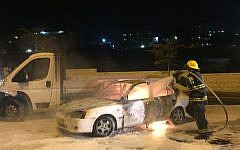 Firefighters extinguish a car that caught fire after it was hit by a Molotov cocktail near the Arab neighborhood of Beit Hanina in East Jerusalem, injuring three people, on Monday night, August 3, 2015 (Sliman Khader/FLASH90)