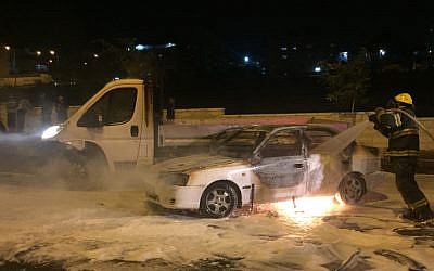 Firefighters extinguish a blazing car after it was hit by a Molotov cocktail near the Arab neighborhood of Beit Hanina in East Jerusalem, August 3, 2015. (Sliman Khader/Flash90)